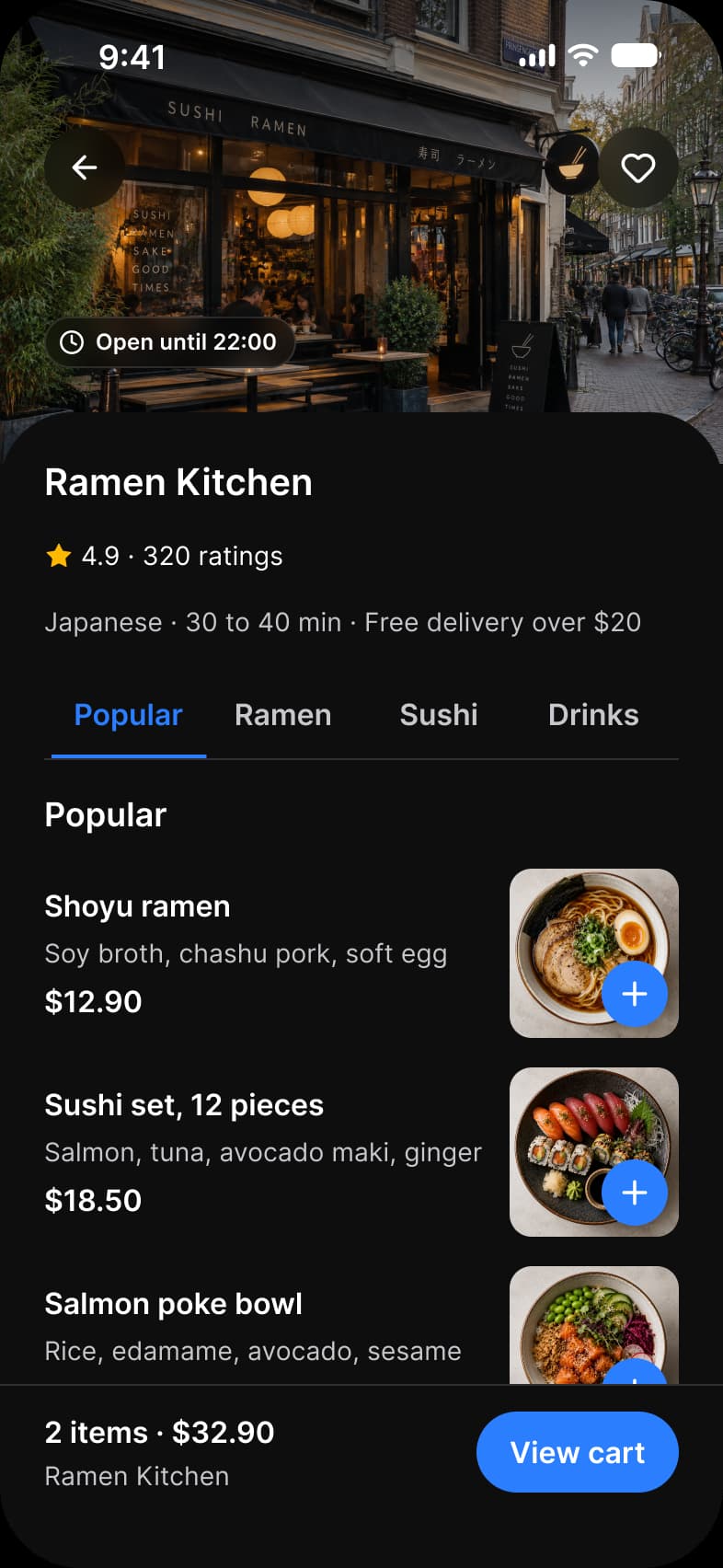 Foodie app Restaurant screen in dark mode: the Ramen Kitchen storefront photo with back and favorite buttons and an Open until 22:00 label, a 4.9 rating from 320 ratings, Popular, Ramen, Sushi and Drinks tabs, dish rows with a price and a blue add button on each photo, and a View cart bar with 2 items and $32.90